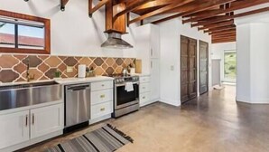 A kitchen with white cabinets, a stone backsplash, and a wooden ceiling.