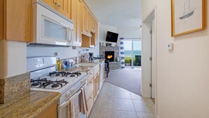 Una cocina moderna con armarios de madera, cocina a gas, microondas y chimenea de piedra.