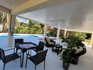 Eine Außenpatio mit Pool, Korbmöbeln und Blumentöpfen.