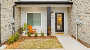 A modern two-story house with a stone facade, a front porch with a wooden chair, and a mailbox. - World Cup Stay in Arlington – Walk to AT&T Stadium (Arlington)