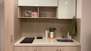 A modern kitchen with a built-in stove, a sink, and a countertop. There are cabinets above the countertop, and a towel hangs on the wall. - Maravilloso loft con vista 707 (Bogotá)