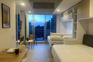 Een kleine hotelkamer met balkon, een bed, een tafeltje met een kopje en een stoel.