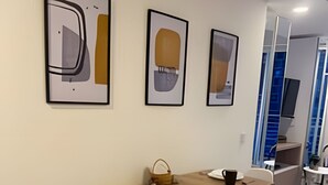 A modern dining area with a wooden table, white chairs, and framed artwork on the wall. - Maravilloso loft con vista 707 (Bogotá)