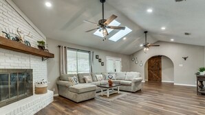 A spacious living room with a fireplace, sectional sofa, and a ceiling fan. - Farm House with an Amazing Pool in the desirable Western Hills in Temple TX (Temple)