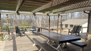A covered outdoor deck with a picnic table and chairs, surrounded by a wooden fence and trees. - Farm House with an Amazing Pool in the desirable Western Hills in Temple TX (Temple)