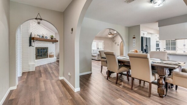 A spacious dining area with a long table and chairs, an arched doorway leading to a kitchen, and a fireplace with a brick wall. - Farm House with an Amazing Pool in the desirable Western Hills in Temple TX (Temple)