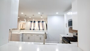 A modern kitchen with white cabinets, a stainless steel sink, and a gas stove. - Miramar Game Room Home Arcade · King Bed  15 Min to Beach (Miramar)