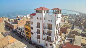 A multi-story building with balconies, a red roof, and a view of the sea. - Blanca Rosa's Place (Pacasmayo)
