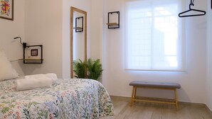 Ein Schlafzimmer mit einem Bett, einer Sitzbank, einem Spiegel und einem Fenster.