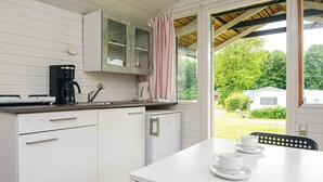 A compact kitchen with white cabinets, a coffee maker, and a view of a green landscape. - 4 Person Holiday Park Home in Jelling (Jelling)