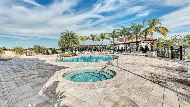 A pool area with two pools, lounge chairs, and palm trees.