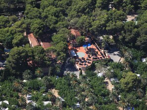 An aerial view of a resort with a central courtyard, surrounded by dense greenery and palm trees. - Cottage in Spain With Private Beach Access (Mont-roig del Camp)