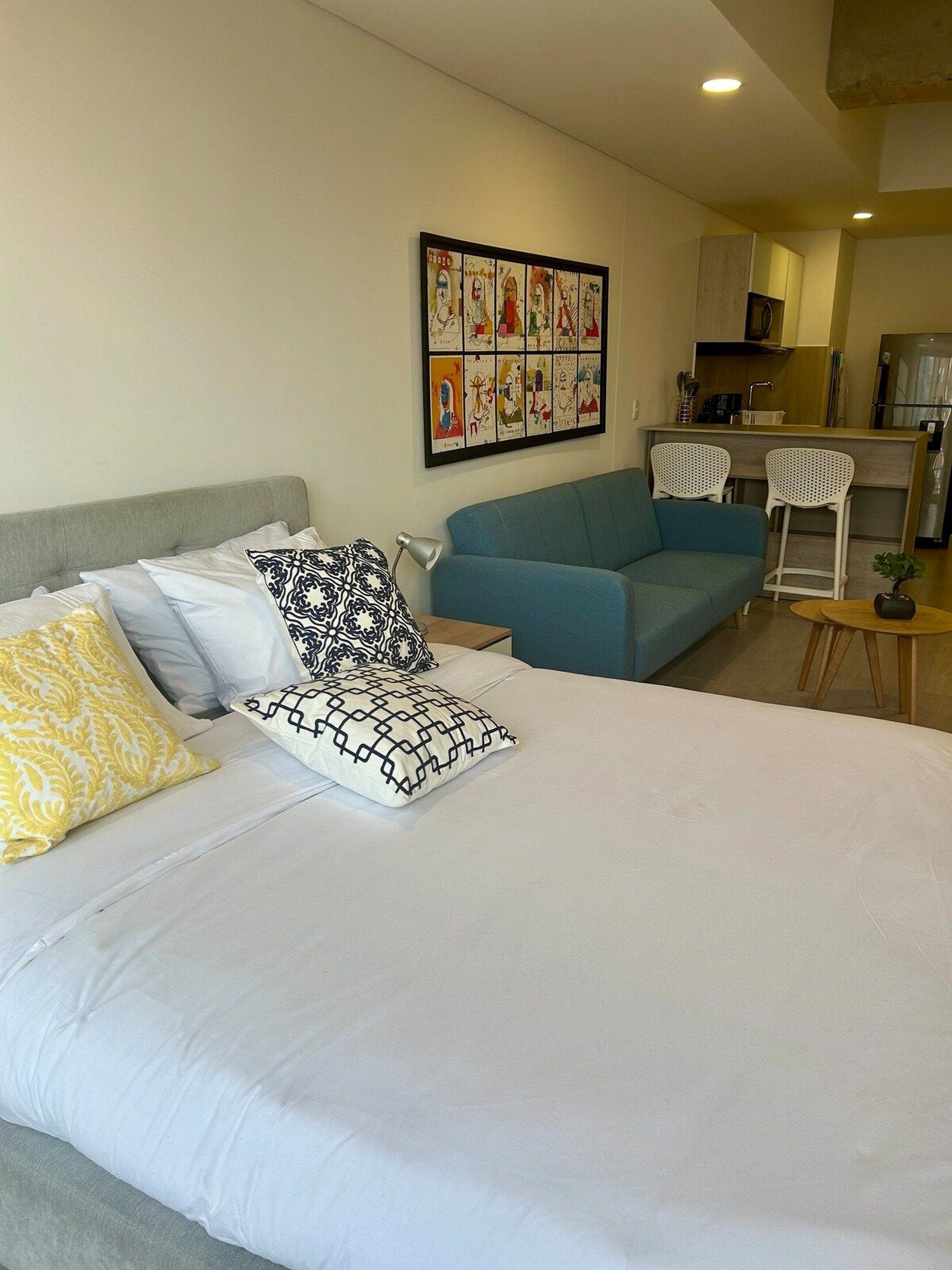 Ein Hotelzimmer mit Bett, einer Couch, einem kleinen Tisch und einer Küchenzeile im Hintergrund.