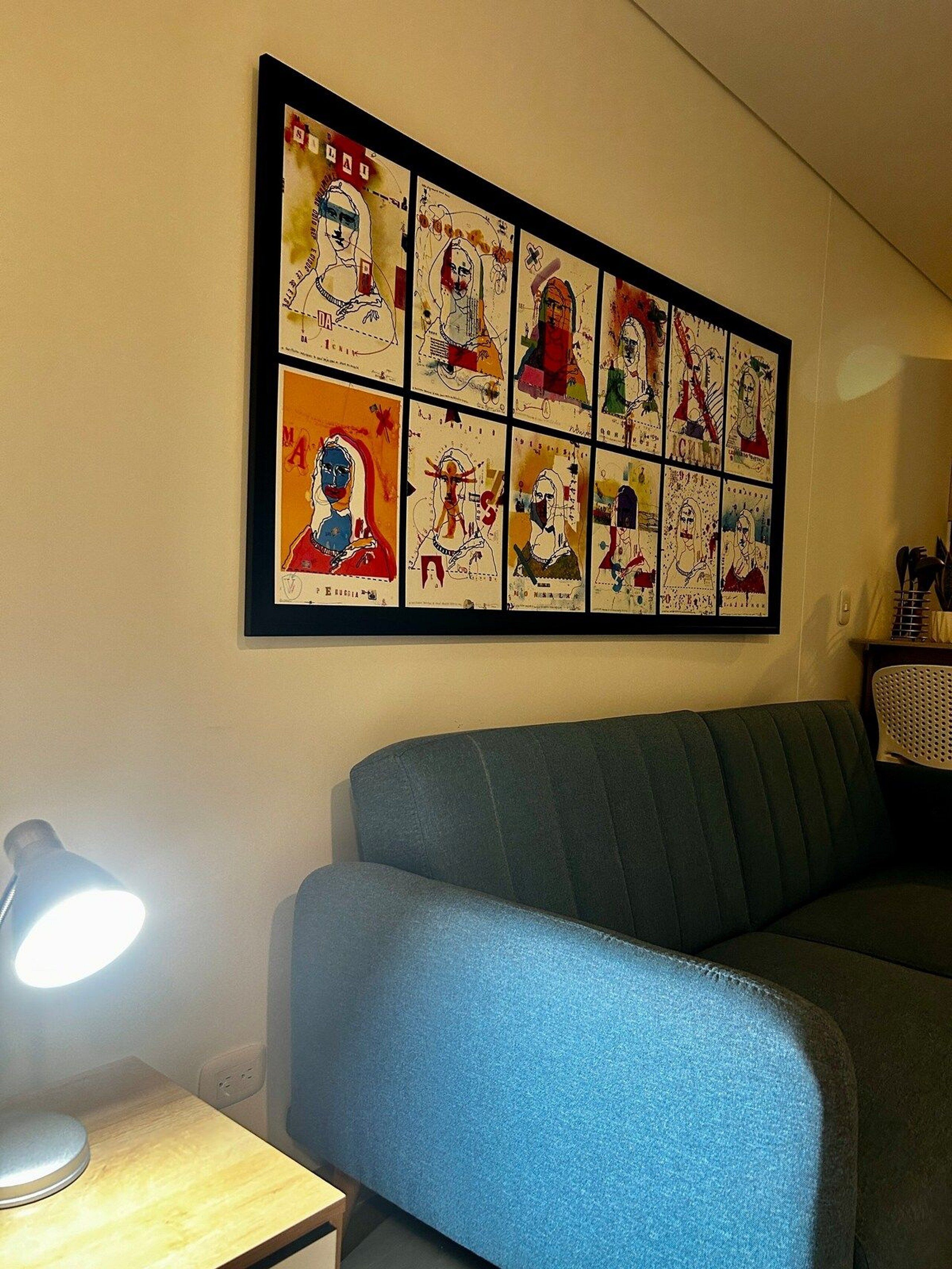 A living room with a blue sofa, a framed artwork on the wall, and a lamp on a side table.
