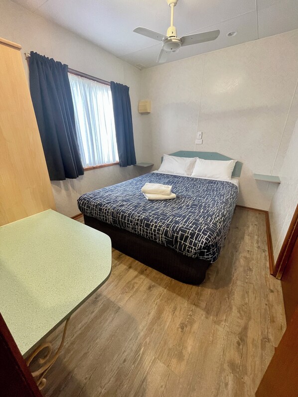 A room with a bed, a desk, a ceiling fan, and a window with curtains. - BIG4 Red Cliffs Holiday Park (Red Cliffs)