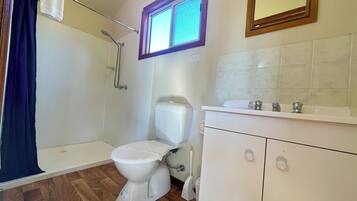 A bathroom with a shower, toilet, sink, and a window.