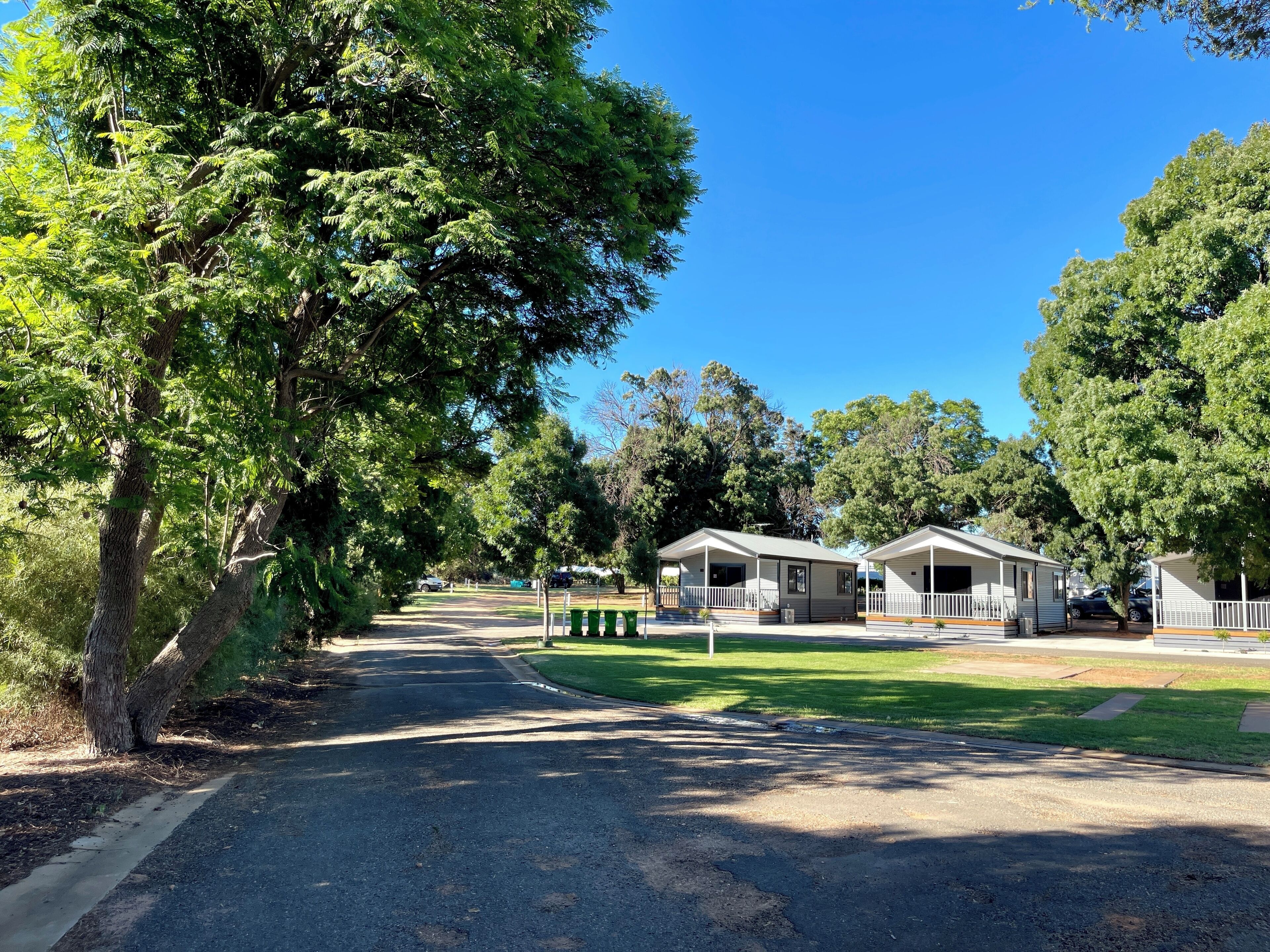 A campground with two mobile homes, a paved road, and surrounding greenery.
