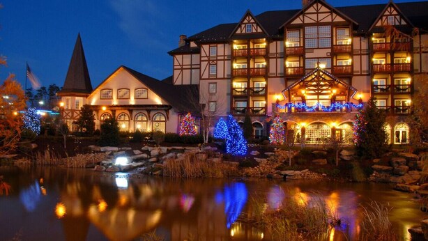A large hotel with multiple stories, a prominent steeple, and a reflective pond in front. - Monarch of the Mountain pool (Pigeon Forge)