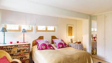 A bedroom with a bed, two bedside tables, a chair, a window, and a door.