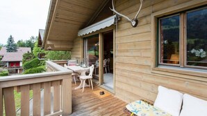 Una baita di legno con veranda, zona pranzo e divano.