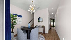 A modern dining area with a round table, grey chairs, a blue vase, and a unique chandelier.