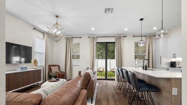 A modern living room with a sofa, TV, and dining area with bar stools.
