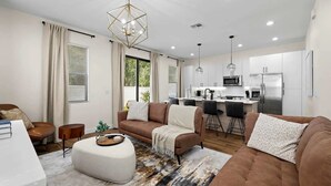 A modern living room with a sofa set, a coffee table, and a dining area with bar stools.