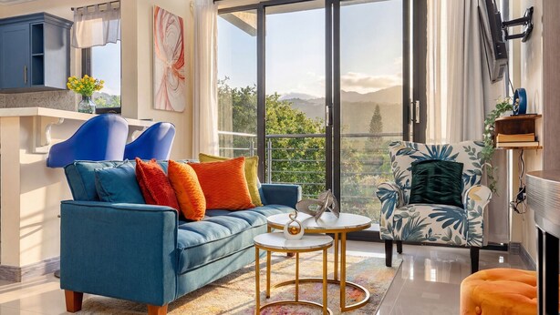 A modern living room with a blue sofa, a round coffee table, and a patterned armchair. - The Blooming Blaze W/ Pool (Kingston)