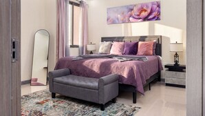 A bedroom with a bed, bedside tables, a chair, a floor lamp, and a large floral artwork on the wall. - The Blooming Blaze W/ Pool (Kingston)