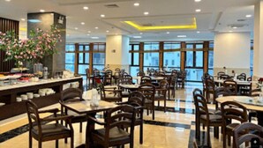 A spacious restaurant with multiple tables and chairs, large windows, and a modern interior design. - Peace Hotel Ha Long (Bai Chay)