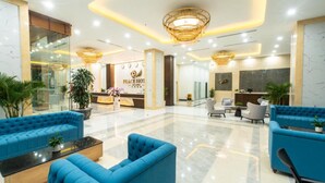 A modern lobby with blue sofas, a reception desk, and a chandelier. - Peace Hotel Ha Long (Bai Chay)