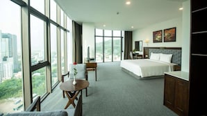 A hotel room with a large bed, a desk, a chair, and a view of the city. - Peace Hotel Ha Long (Bai Chay)