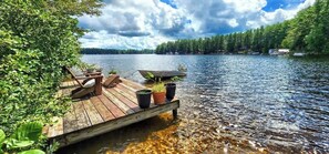 A wooden dock extending into a lake with a boat moored at the end. - Private Island, 5 Homes, 2 HotTub, Boat -Sleeps 17 (Greig)