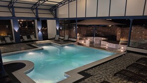 A swimming pool with lounge chairs and a sunbed area, surrounded by stone walls and a tiled floor. - Tathastu Satpura (Shahpur)