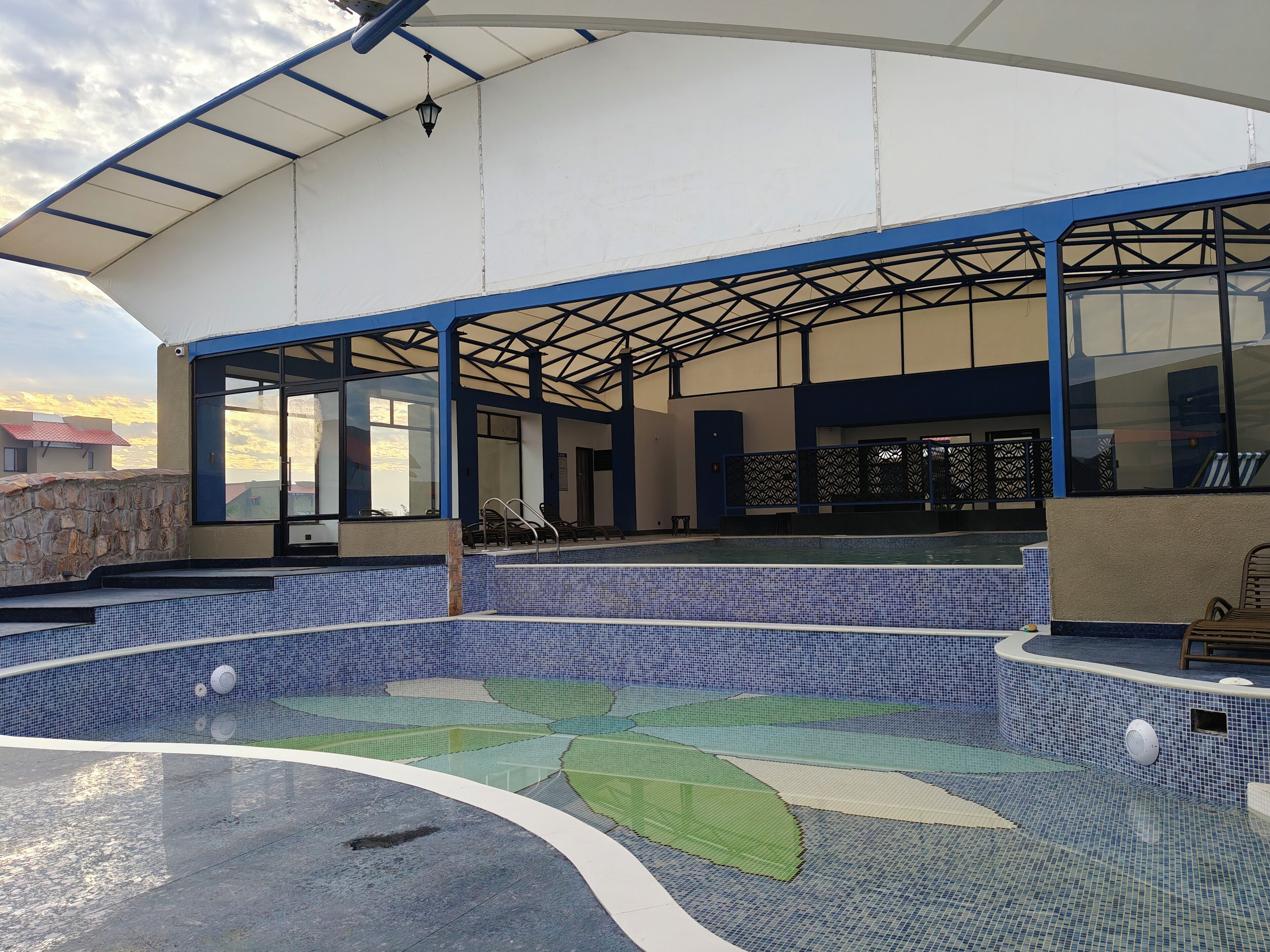 Una piscina techada con diseño de azulejos azules y blancos, un muro de piedra y vistas del entorno.