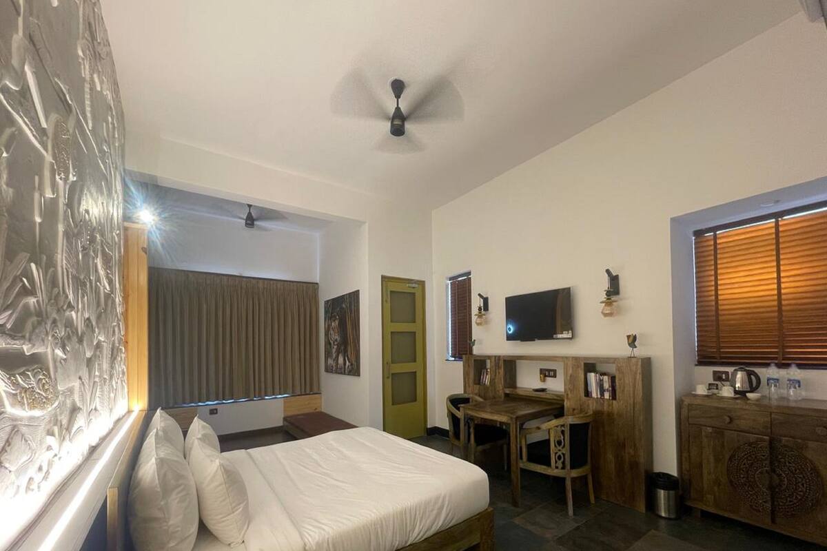 Une chambre à coucher avec un lit, un bureau, une télévision et une fenêtre avec des stores.