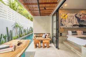 A modern room with a pool, wooden furniture, and a large abstract painting. - Ubud Lila Concept (Ubud)