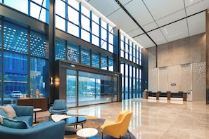 A spacious lobby with a reception desk, seating area, and large windows offering views of the outside. - Hampton BY Hilton Shenzhen Yuanshan (Shenzhen)