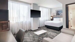 Een hotelkamer met een bed, een aan de muur bevestigde televisie, een tafeltje en een sofa.