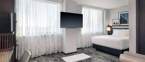 Una habitación de hotel con cama, televisión, escritorio y silla.