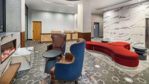 Een moderne lobby met een open haard, zithoeken en een marmeren wand.