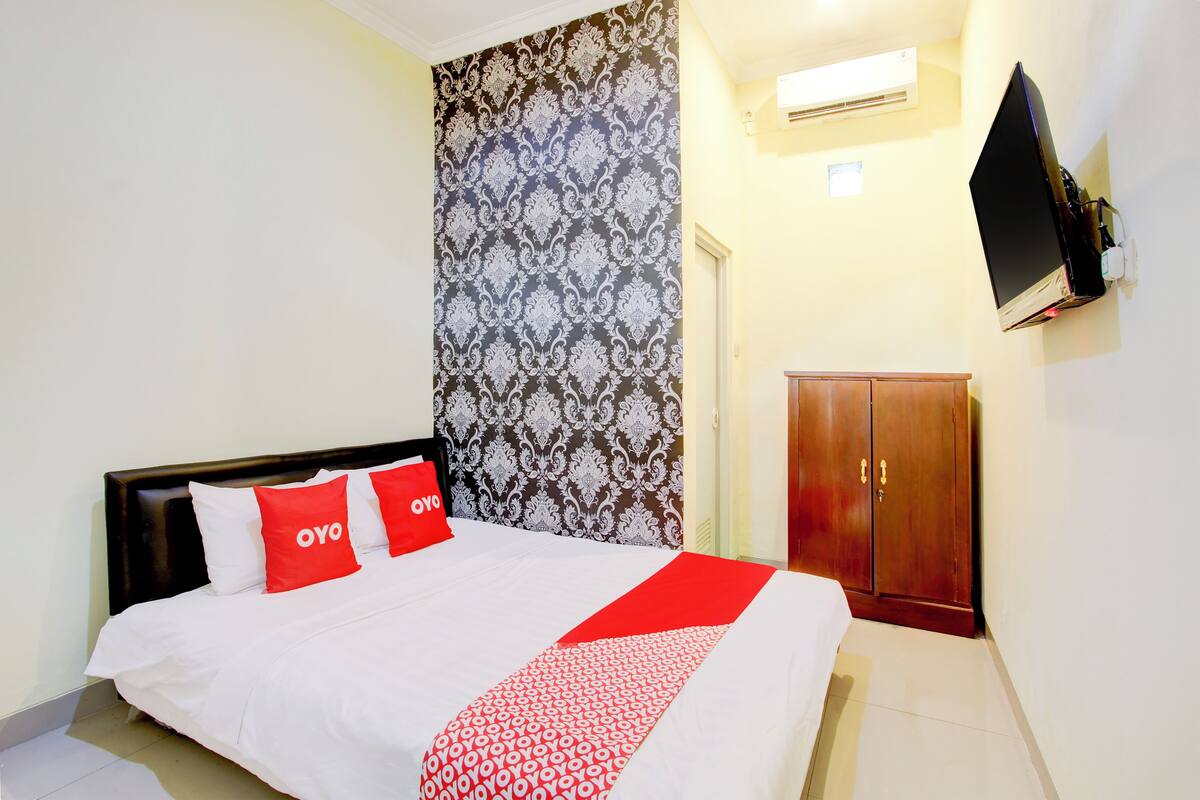 Une chambre d’hôtel équipée d’un lit, d’une armoire et d’un téléviseur fixé au mur.