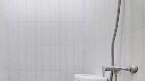 A bathroom with a toilet, a shower, and tiled walls. - Hotel O Sleman Near Bandara Adi Sutjipto Formerly Joglo Sorogenen (Ngemplak)