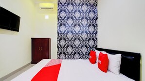 A hotel room with a bed, a wardrobe, a television, and a patterned curtain. - Hotel O Sleman Near Bandara Adi Sutjipto Formerly Joglo Sorogenen (Ngemplak)