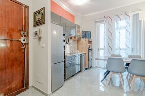 Eine moderne Küche mit Edelstahlgeräten, einer Holztür und einem Essbereich mit Tisch und Stühlen.