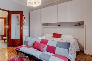 Ein Schlafzimmer mit einem Bett, einem Schlafsofa, einem Kleiderschrank und einem Spiegel.