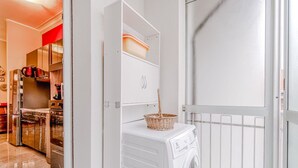 A laundry room with a washing machine, a basket, and a door leading to a kitchen area. - Cozy 50 sqm apartment for 3 people, located on the sixth floor with an elevator (not suitable for people with disabilities). Just 100 meters from the Carducci Metro station, the apartment features a large terrace. Located in a well-served area of Turin,  (Torino)