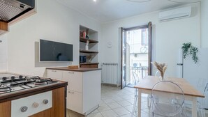 A modern kitchen with a gas stove, white cabinets, and a dining area with a wooden table and clear chairs. - GuestHost - Comfortable apartment, able to accommodate up to 4 people. The accommodation is located in a refined period building in the center of Turin, a few meters from Piazza Castello and the Royal Palace, a short distance from every essential service (Torino)