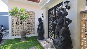 A courtyard with a statue, a potted plant, and a decorative fence. - Collection O Samurai Hotel (Denpasar)