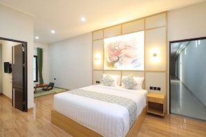 A modern hotel room with a large bed, a wooden nightstand, a wall-mounted painting, and a sliding door leading to a bathroom. - Collection O Samurai Hotel (Denpasar)
